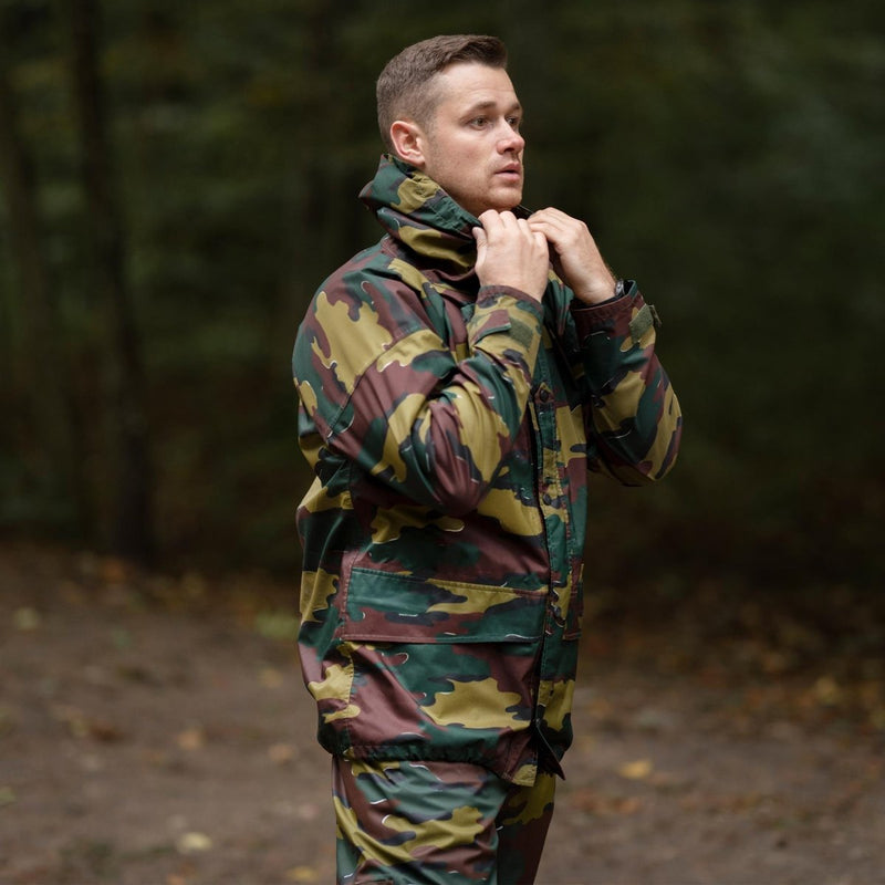 Man wearing Genuine Belgian Army waterproof GoreTex jigsaw camo parka with hood in outdoor forest setting