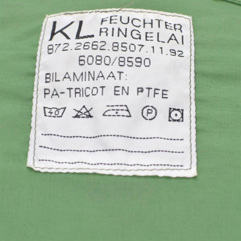 Close-up of Dutch army parka liner care label showing fabric composition and washing instructions on olive green fabric