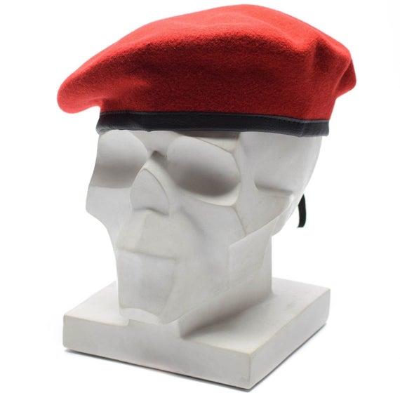 Genuine German army red wool beret displayed on a white modern sculpture head model with black trim band.