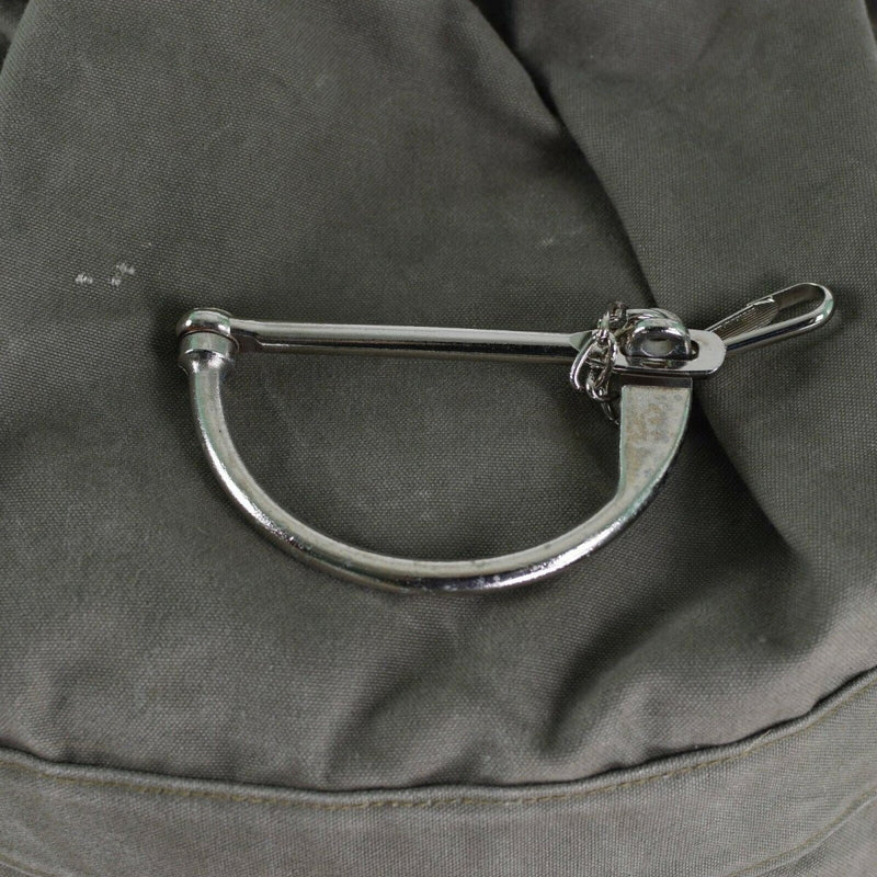 Close-up of metal lock mechanism on genuine German army sea sack duffel bag with green fabric background