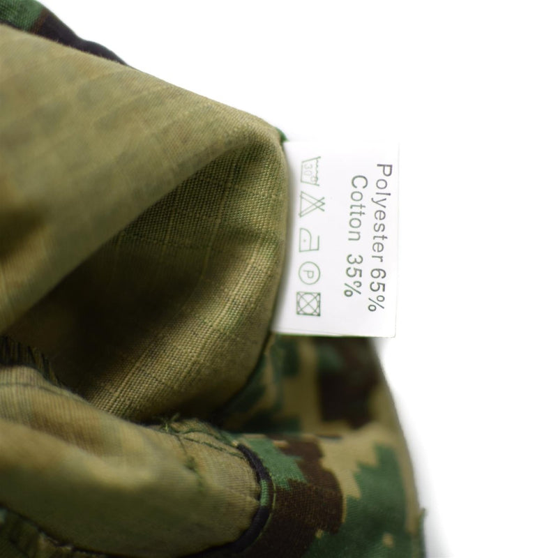 Close-up of fabric label showing 65% polyester and 35% cotton in genuine Guinea Bissau jungle camouflage pants