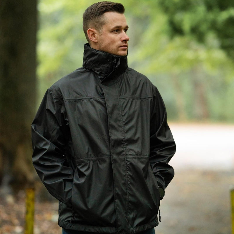 Man wearing Mil-Tec black waterproof rain jacket with high collar in forested outdoor setting