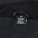 Close-up of MIL-TEC jacket fabric and size tag showing material composition and care details in black softshell material