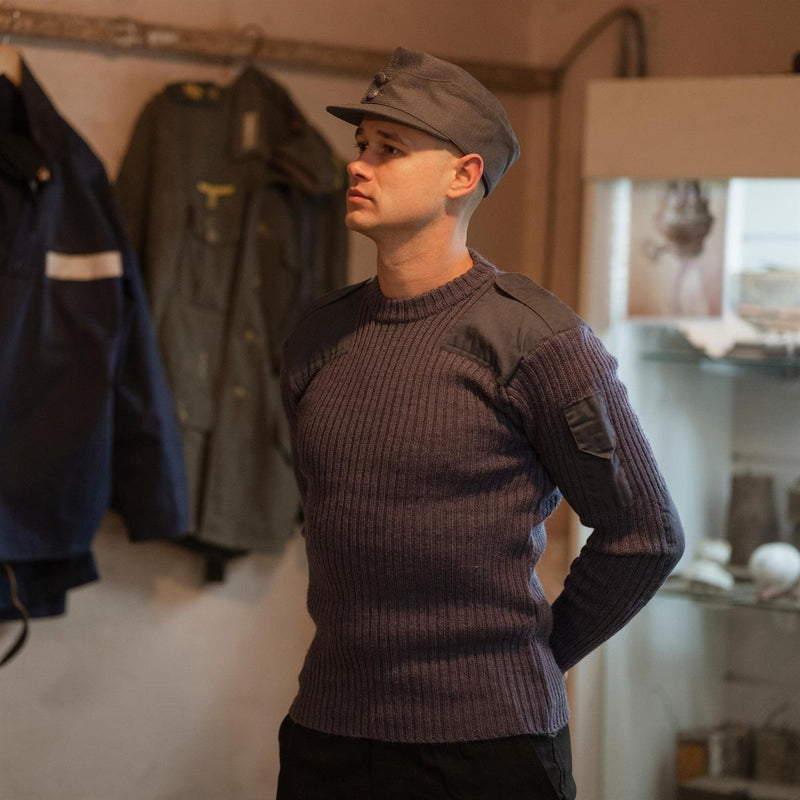 Man wearing original British army commando jumper blue grey wool sweater with reinforced patches indoors
