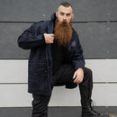 Man wearing original dark blue Dutch police military surplus parka jacket with hood standing against gray wall