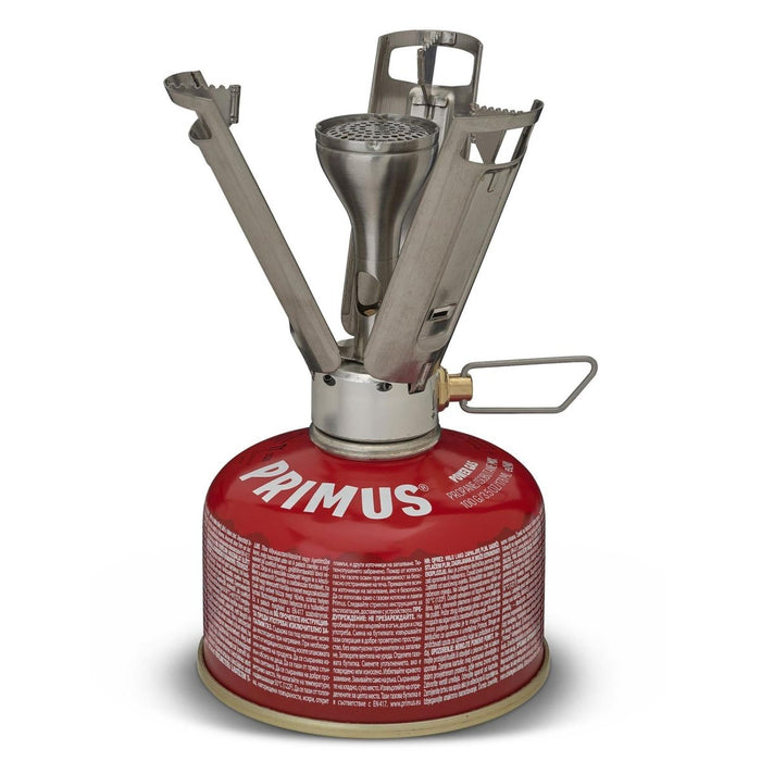 Réchaud de camping léger Primus Firestick Titanium monté sur une cartouche de gaz rouge avec supports de casseroles dépliés.