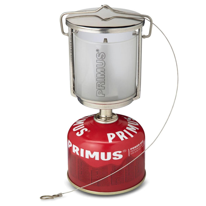 Lanterne de camping portable Primus Mimer avec corps en acier inoxydable et verre dépoli sur bidon de gaz rouge.