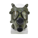 Vintage Romanian M74 full face NBC gas mask in olive green with dual eyepieces and exhale valve displayed on white stand.