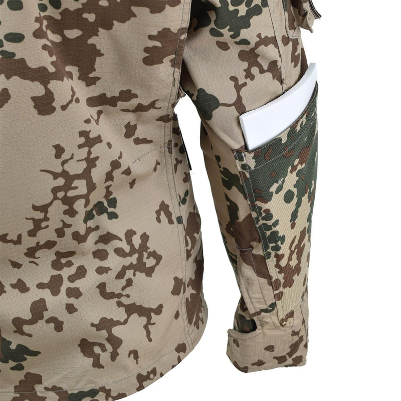 Close-up of TACGEAR desert flecktarn camo combat shirt sleeve with reinforced elbow and pocket holding a white item